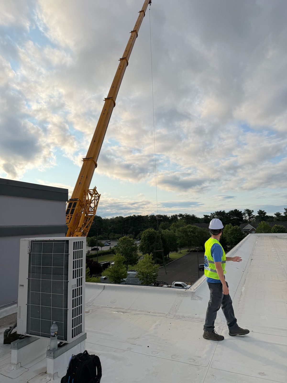 Crane staged beside an office center for a rooftop unit replacement