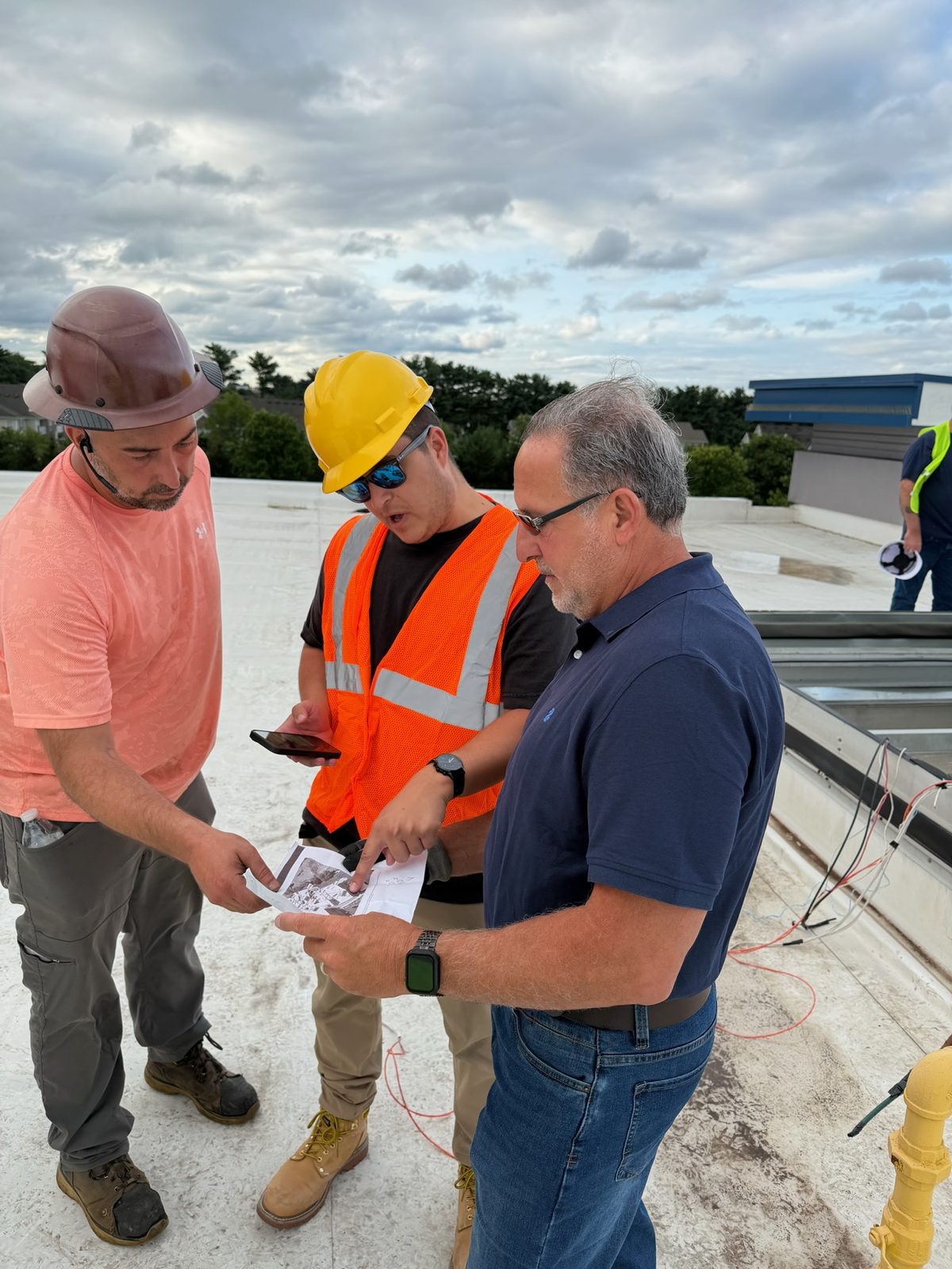 Rooftop HVAC crew reviewing mechanical drawings on site before a rooftop unit installation