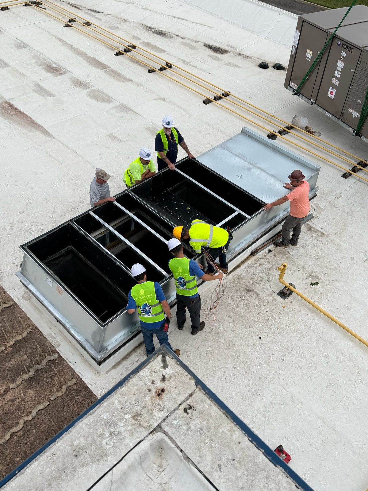 Rooftop HVAC crew positioning a curb adapter during a commercial rooftop unit changeout