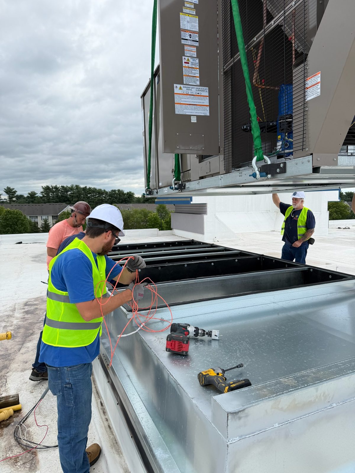 Technician making duct connections at the curb during a commercial rooftop unit replacement