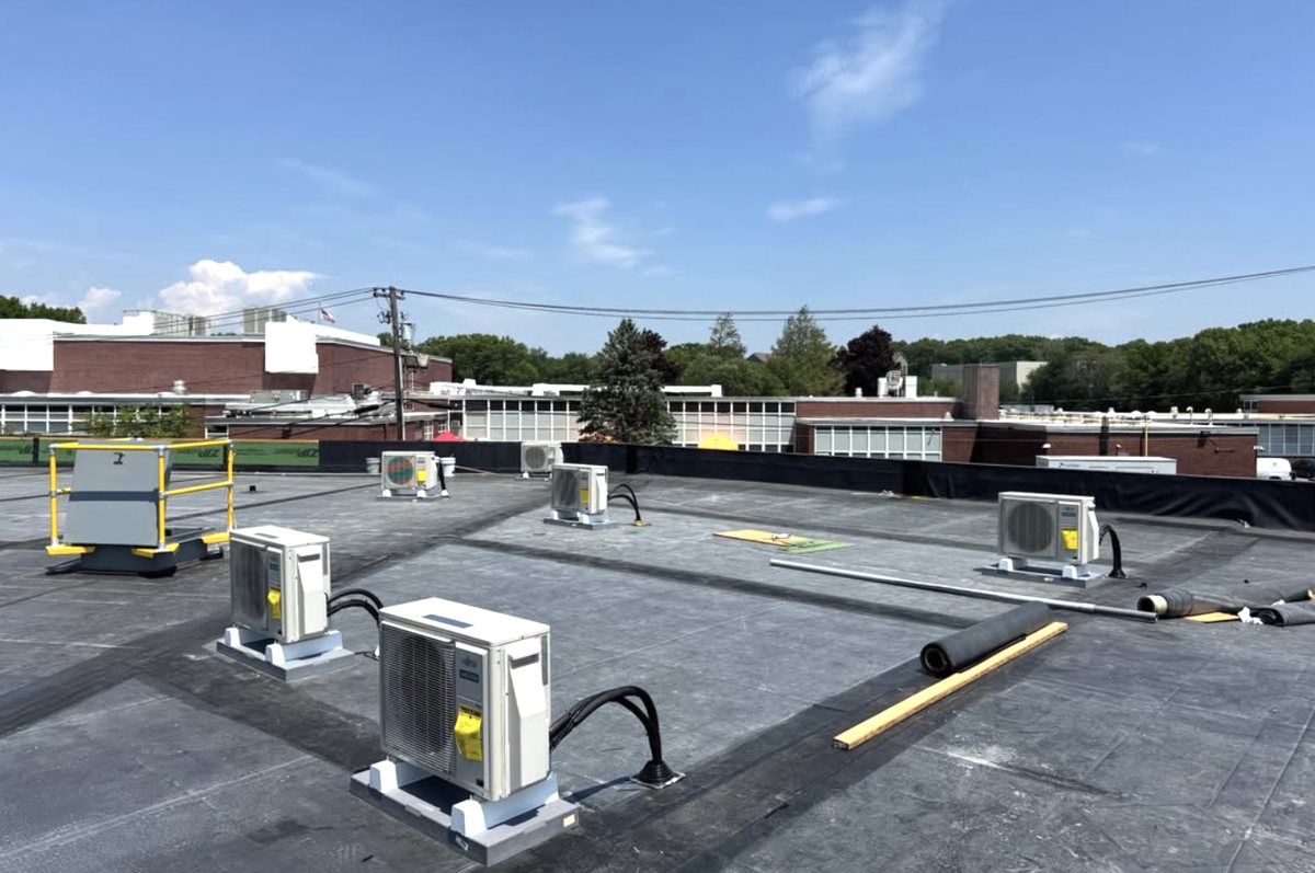 Ductless split condensing units set on pads across a flat commercial roof