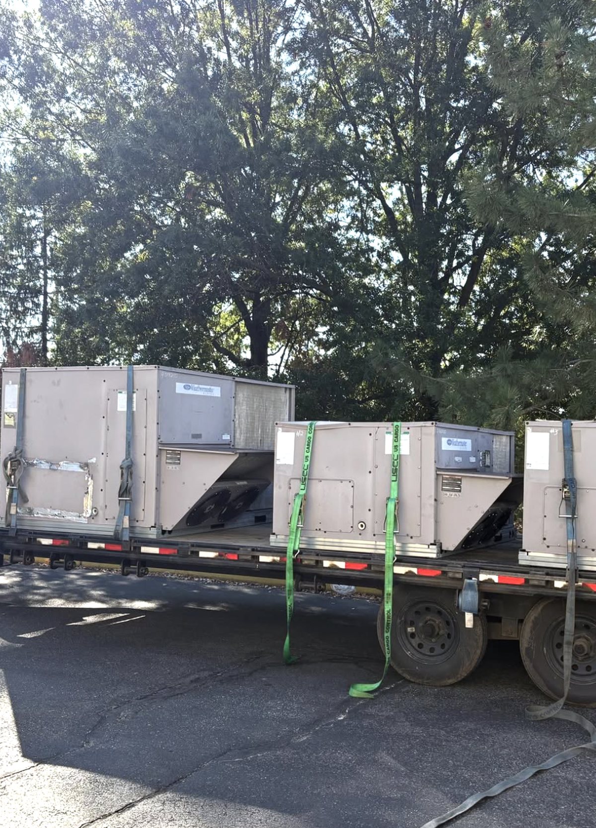 Three new rooftop units strapped to a flatbed trailer before installation