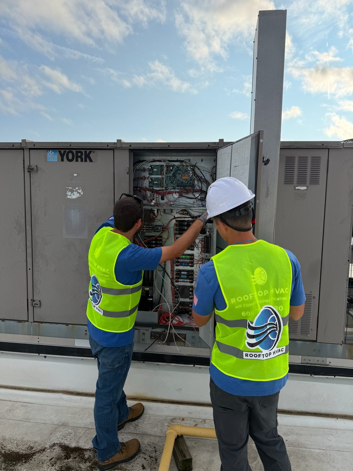 Technician working inside the control panel of a commercial rooftop unit